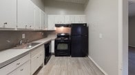 Located at 3214 Valley Bluff Dr in Atlanta, GA, this single-floor residence showcases a distinctive mid-century-inspired architectural character, highlighted by white-painted shiplap ceilings with exposed beams that run throughout the main living areas, lending a warm and textured ambiance to each room.

The living area is open and airy, featuring durable hardwood-style flooring in a cool gray tone and a sliding glass door that connects directly to a private outdoor deck, filling the space with natural light and offering pleasant outdoor views. An adjacent dining or secondary living area continues the same flooring and beamed ceiling design, with direct sightlines into the kitchen.

The kitchen is thoughtfully laid out with ample white cabinetry, a neutral countertop with an integrated sink, and full-size black appliances including an electric range and refrigerator, all set atop light wood-look flooring.

The bedrooms feature plush carpet flooring and the same characteristic shiplap ceilings, with windows that allow natural light to brighten each room. The bathroom is well-appointed with a full tub-shower combination featuring tile surround, a wide vanity with a stone-finish countertop, dual sinks, a large mirror, and wood-look flooring.

Neutral gray walls throughout the home create a clean, cohesive palette that complements the architectural details and makes the space feel move-in ready.