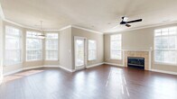 Located at 308 Augusta Way in Fort Wayne, Indiana, this two-story home offers three bedrooms and two bathrooms thoughtfully arranged across two levels. The main living level is expansive, hosting an open-concept living room, dining room, and kitchen. The living room is a standout space, featuring rich hardwood-style flooring, crown molding, a ceiling fan, and a tile-surround fireplace flanked by large windows that flood the room with natural light. A glass door opens to the balcony, extending the living space outdoors. The kitchen is equipped with white cabinetry, light countertops, and black appliances, including a refrigerator and range, with an adjacent pantry for added storage. A dedicated laundry room with in-unit washer hookups adds everyday convenience. The three bedrooms are carpeted and well-lit by natural light, with the generously sized primary bedroom featuring its own walk-in closet fitted with extensive wire shelving. The two bathrooms are finished with white vanities and hardwood-style flooring. Throughout the home, eight closets provide exceptional storage. The lower level includes an attached garage with an automatic opener. Two staircases connect the levels, with carpeted stairs and a white handrail visible from the entry.