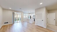 Located at 1800 Silas Deane Highway in Rocky Hill, Connecticut, this thoughtfully designed single-floor unit offers a bright, modern living experience with a clean, neutral aesthetic throughout. The open-concept layout seamlessly connects the kitchen and living room, creating a spacious and functional shared area filled with natural light from large windows and sliding glass doors that lead to a private balcony overlooking the outdoors.

The kitchen is a standout feature, showcasing crisp white shaker cabinetry with matte black hardware, a large central island with a white quartz countertop and undermount sink, stainless steel appliances including a gas range and refrigerator, a subway tile backsplash, and stylish pendant lighting overhead. The living area flows naturally from the kitchen and features light hardwood flooring and recessed lighting that carries throughout the unit.

The bathroom is finished in a clean, modern style with white tile flooring, a white vanity with quartz countertop, a lighted mirror, and matte black fixtures. Two closets provide ample storage, and a dedicated laundry area adds everyday convenience. The consistent use of light tones, recessed lighting, and hardwood flooring throughout creates a cohesive, airy ambiance that feels both contemporary and welcoming.