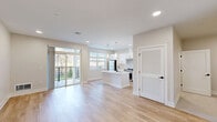 Located at 1800 Silas Deane Highway in Rocky Hill, Connecticut, this thoughtfully designed single-floor unit offers a bright, modern living experience with a clean, neutral aesthetic throughout. The open-concept layout seamlessly connects the kitchen and living room, creating a spacious and functional shared area filled with natural light from large windows and sliding glass doors that lead to a private balcony overlooking the outdoors.

The kitchen is a standout feature, showcasing crisp white shaker cabinetry with matte black hardware, a large central island with a white quartz countertop and undermount sink, stainless steel appliances including a gas range and refrigerator, a subway tile backsplash, and stylish pendant lighting overhead. The living area flows naturally from the kitchen and features light hardwood flooring and recessed lighting that carries throughout the unit.

The bathroom is finished in a clean, modern style with white tile flooring, a white vanity with quartz countertop, a lighted mirror, and matte black fixtures. Two closets provide ample storage, and a dedicated laundry area adds everyday convenience. The consistent use of light tones, recessed lighting, and hardwood flooring throughout creates a cohesive, airy ambiance that feels both contemporary and welcoming.