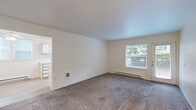 This well-organized 2-bedroom, 1-bathroom single-floor unit offers a functional and comfortable layout. The carpeted living room is bright and open, featuring a large window and a door that leads to the outdoors, filling the space with natural light and views of surrounding greenery. A baseboard heating system runs throughout the main living areas, ensuring consistent warmth. The galley-style kitchen is efficiently designed with white cabinetry lining both walls, light wood-look flooring, white appliances including an electric range and refrigerator, and a window above the sink that provides additional natural light. Adjacent to the kitchen is a dining area with light wood-look flooring, a ceiling fan, and a window. The generously sized primary bedroom offers ample space, plush carpeting, and built-in shelving, while the second bedroom features carpet flooring, a window, and a baseboard heater. Both bedrooms provide comfortable, functional spaces. A dedicated closet area near the entry includes a rod closet and open built-in shelving for organized storage. The bathroom features light wood-look flooring, a bathtub and shower combination, a linen storage tower, and clean white finishes throughout, creating a simple and practical space.