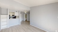 Located at 7760 McCallum Blvd in Dallas, TX, this one-bedroom, one-bathroom unit offers a practical and efficiently designed layout across a single floor. The open-concept living, dining, and kitchen area is unified by light wood-look flooring and a neutral gray color palette, creating a clean and cohesive aesthetic. A textured ceiling and crisp white baseboards add architectural character throughout the main living space. Large sliding glass doors in the living area flood the room with natural light and provide direct access to a private balcony, offering outdoor views of the surrounding community. The kitchen features white cabinetry, a gray subway tile backsplash, white countertops, a stainless steel sink, and black appliances including a refrigerator and range. A built-in shelving unit adds additional storage and display space to the living area. The bedroom is carpeted for comfort, includes a ceiling fan, and benefits from natural light through a window with blinds. The bathroom is outfitted with a full tub-shower combination with white tile surround. Three closets throughout the unit provide generous storage, and a dedicated laundry area adds everyday convenience.