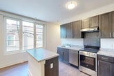 Located in Washington, DC's Bates Street corridor, this two-story residence offers a well-organized layout across two distinct levels. The main floor hosts an open-concept living, dining, and kitchen area that maximizes the available footprint. The kitchen is outfitted with dark espresso cabinetry, granite-style countertops, a stainless steel sink, a smooth-top range, an under-cabinet range hood, and a striking hexagonal tile backsplash that adds a contemporary accent. A window at the end of the living area admits natural light and views of the surrounding neighborhood. Warm hardwood-style flooring runs throughout both levels, lending a cohesive aesthetic. A modern staircase with a sleek black metal railing connects the two floors, serving as a functional design feature. A full bathroom with a tub-shower combination, white square tile surround, and dark vanity cabinetry is also accessible on this level. The upper floor is dedicated to the private bedroom, which features a large multi-pane window with city views, two closets with double doors, and access to a hallway leading to an additional bathroom. Two closets provide generous storage. The overall design is clean, modern, and efficient, making thoughtful use of every square foot across both floors.