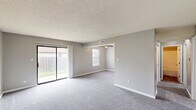 Located at 1901 East Walnut Street in Columbia, Missouri, this single-floor, 2-bedroom, 1-bathroom unit offers a practical and comfortable layout across a well-proportioned floor plan. Neutral gray walls and white trim carry throughout, creating a clean, cohesive aesthetic in every room.

The living area is generously sized, featuring plush gray carpet and a sliding glass door that fills the room with natural light and provides direct access to an outdoor greenspace. A second living area offers additional flexible space near the entry, also finished with carpet and a front-facing door.

Both bedrooms are carpeted and equipped with ceiling fans with built-in lighting. Each room includes natural light from windows with blinds, and both feature closets — one with a bifold door configuration. The primary bedroom offers a comfortable sense of space with its own closet and direct access to the hallway.

The kitchen is outfitted with white cabinetry, granite-style countertops, wood-look vinyl plank flooring, and a full-size refrigerator, providing a functional and updated cooking space. The bathroom includes a full tub-shower combination with clean white surround and brushed nickel fixtures.

A connecting hallway ties the layout together efficiently, making this a well-organized unit suitable for everyday living.