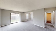 Located at 1901 East Walnut Street in Columbia, Missouri, this single-floor, 2-bedroom, 1-bathroom unit offers a practical and comfortable layout across a well-proportioned floor plan. Neutral gray walls and white trim carry throughout, creating a clean, cohesive aesthetic in every room.

The living area is generously sized, featuring plush gray carpet and a sliding glass door that fills the room with natural light and provides direct access to an outdoor greenspace. A second living area offers additional flexible space near the entry, also finished with carpet and a front-facing door.

Both bedrooms are carpeted and equipped with ceiling fans with built-in lighting. Each room includes natural light from windows with blinds, and both feature closets — one with a bifold door configuration. The primary bedroom offers a comfortable sense of space with its own closet and direct access to the hallway.

The kitchen is outfitted with white cabinetry, granite-style countertops, wood-look vinyl plank flooring, and a full-size refrigerator, providing a functional and updated cooking space. The bathroom includes a full tub-shower combination with clean white surround and brushed nickel fixtures.

A connecting hallway ties the layout together efficiently, making this a well-organized unit suitable for everyday living.