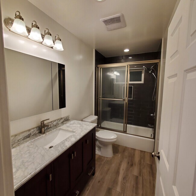 Baño completo principal con tocador italiano Carrera con superficie de mármol y armario con espejo doble Kohler. - 5731 Fulton Ave