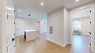 This well-appointed 3-bedroom, 2-bathroom residence at 196 Dayton Avenue in Passaic, NJ offers a thoughtfully designed single-floor layout with generous living space. Light wood flooring flows throughout, complemented by neutral-toned walls and clean white trim that create a bright, cohesive aesthetic. The open-concept kitchen and living area serves as the heart of the home, featuring a sleek, contemporary kitchen outfitted with dark navy cabinetry, a subway tile backsplash, stainless steel appliances including a gas range, built-in microwave, and refrigerator, along with a central island with a crisp white countertop and pendant lighting above. The spacious living room benefits from recessed lighting and large windows that bring in natural light. Each of the three bedrooms offers comfortable proportions, large windows with roll-up shades, individual climate control units, and warm wood-tone flooring. The generously sized primary bedroom provides ample room for a full furniture arrangement. Both bathrooms are finished to a modern standard, each featuring a tub-shower combination enclosed by a sliding glass door with dark framing, large-format tile surrounds, a wood-tone vanity, and a framed mirror. Two closets provide practical storage throughout the unit.