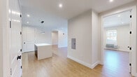 This well-appointed 3-bedroom, 2-bathroom residence at 196 Dayton Avenue in Passaic, NJ offers a thoughtfully designed single-floor layout with generous living space. Light wood flooring flows throughout, complemented by neutral-toned walls and clean white trim that create a bright, cohesive aesthetic. The open-concept kitchen and living area serves as the heart of the home, featuring a sleek, contemporary kitchen outfitted with dark navy cabinetry, a subway tile backsplash, stainless steel appliances including a gas range, built-in microwave, and refrigerator, along with a central island with a crisp white countertop and pendant lighting above. The spacious living room benefits from recessed lighting and large windows that bring in natural light. Each of the three bedrooms offers comfortable proportions, large windows with roll-up shades, individual climate control units, and warm wood-tone flooring. The generously sized primary bedroom provides ample room for a full furniture arrangement. Both bathrooms are finished to a modern standard, each featuring a tub-shower combination enclosed by a sliding glass door with dark framing, large-format tile surrounds, a wood-tone vanity, and a framed mirror. Two closets provide practical storage throughout the unit.