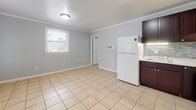 Located in North Chesterfield, VA, this efficient one-bedroom, one-bathroom residence offers a well-organized single-floor layout designed to maximize every square foot. Light-toned ceramic tile flooring runs consistently throughout the entire space, creating a clean, cohesive look.

The combined kitchen and living area serves as the heart of the home. The kitchen is outfitted with rich dark-brown cabinetry, a tile backsplash, light countertops, and white appliances including a refrigerator and range. A stacked washer and dryer unit is conveniently integrated into the kitchen area. The open living space adjoins the kitchen, featuring soft gray walls, crown molding, and a window that brings in natural light.

The bedroom is a well-proportioned retreat with the same tile flooring, crown molding, gray walls, and a window providing natural light and outdoor views. A closet offers dedicated storage, keeping the space organized and functional.

The bathroom is clean and bright, featuring a white vanity with ample counter space, a toilet, and tile flooring consistent with the rest of the home. Chrome fixtures and white walls contribute to a crisp, tidy atmosphere.

Crown molding details carried throughout the space add a thoughtful architectural touch, elevating the overall character of this practical and move-in-ready residence.