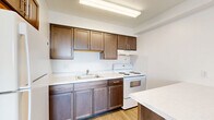 Located at 125 E 156th St in Cleveland, Ohio, this 2-bedroom, 1-bathroom unit offers a practical and well-organized single-floor layout. Throughout the space, light wood laminate flooring and crisp white walls create a clean, bright aesthetic that maximizes the sense of openness.

The living area benefits from natural light streaming through a large window fitted with vertical blinds, casting warm light across the floors. The kitchen, visible in the dollhouse view, features dark cabinetry, a white refrigerator, and a standard range with overhead storage — a functional setup designed for everyday use.

The primary bedroom is generously sized and includes an open closet with a full-width hanging rod, providing ample storage. A second bedroom also features a window with vertical blinds and its own closet with sliding panel doors. Both bedrooms receive natural light and share the same cohesive wood-tone flooring. A third room functions as a compact additional space with a built-in wall heater and window views of the surrounding urban streetscape.

The bathroom is outfitted with a full soaking tub and shower combination, complete with chrome fixtures, a grab bar, and light-toned wall surround panels atop classic tile flooring. The overall design is straightforward and functional, suited for comfortable everyday living in the Cleveland area.