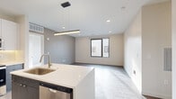 Located at 4201 S Navajo St in Englewood, Colorado, this single-floor residence showcases a contemporary design with clean lines and modern finishes throughout. The open-concept living and kitchen area serves as the heart of the space, where light-toned luxury vinyl plank flooring flows seamlessly underfoot. A standout kitchen features two-tone cabinetry — dark wood-grain lower cabinets paired with high-gloss white upper cabinets — complemented by white quartz countertops, under-cabinet lighting, and a full suite of stainless steel appliances. A generously sized center island with an integrated sink and a sleek linear pendant light above anchors the space, opening directly to the living area, which receives natural light through black-framed windows. The bedrooms offer plush carpeting, ceiling fans, and ample natural light, while one room features durable luxury vinyl plank flooring. A well-appointed walk-in closet includes custom dark-finish built-in shelving, hanging rods, and integrated drawers. The bathroom presents a dual-sink vanity with dark wood-grain cabinetry, white quartz countertops, backlit mirrors, brushed nickel fixtures, and large-format tile flooring, contributing to the space's cohesive, modern aesthetic.