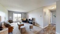 This well-appointed two-bedroom, two-bathroom residence in Bloomington, Minnesota offers a thoughtfully designed single-floor layout. The spacious living room serves as the heart of the home, featuring plush carpet, neutral gray walls, a textured ceiling, and a large sliding glass door that opens to a private balcony with outdoor views — filling the space with natural light. The entry transitions seamlessly from wood-look vinyl plank flooring into the carpeted living area, adding visual contrast and practicality.

The kitchen is efficiently laid out with gray cabinetry, a light quartz-style countertop, wood-look plank flooring, and black appliances including a refrigerator and electric range. It flows directly into the dining area, creating a functional cooking and entertaining space.

The generously sized primary bedroom offers a calm, neutral palette, plush carpet, a baseboard heating unit, and a window overlooking greenery. The second bedroom is versatile, with carpet, natural light, and ample room for a home office or guest setup. Two closets provide dedicated storage, including a walk-in with wire shelving. Both bathrooms feature tile flooring, gray vanity cabinetry, and a shower-tub combination. A hallway connects all rooms cohesively throughout the residence.