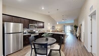 Located at 1243 Coffeeberry Ln in Aurora, IL, this well-appointed single-story home offers 2 bedrooms and 2 bathrooms within a thoughtfully designed open-concept floor plan. The kitchen and living area form the heart of the home, showcasing vaulted ceilings with pendant lighting, dark espresso cabinetry, granite countertops, and a full suite of stainless steel appliances. A kitchen island with additional seating flows naturally into the dining area and living room, which features hardwood-style flooring, a ceiling fan, and access to a patio with natural light streaming in from sliding glass doors. The living room offers a comfortable, airy atmosphere accentuated by the soaring ceiling line. Both bedrooms are carpeted and generously sized, each equipped with ceiling fans and windows that bring in outdoor views. The primary bedroom provides a quiet retreat with ample space and natural light. The bathrooms are finished with granite-topped dark vanities and hardwood-style flooring, with one bathroom conveniently housing an in-unit washer and dryer. The attached two-car garage adds practical storage and parking. Neutral tones throughout lend the home a clean, cohesive aesthetic.