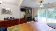 This multi-story property spans three floors and offers a thoughtfully arranged layout with a variety of functional spaces. The living room serves as a central gathering area, highlighted by a striking floor-to-ceiling brick fireplace that anchors the room with warmth and character. Hardwood flooring flows throughout, and a ceiling fan complements the natural light that filters in through sliding glass doors leading to an outdoor view of lush greenery.

The kitchen is well-equipped with warm oak cabinetry, ample counter space, a gas range, refrigerator, dishwasher, and microwave. It opens toward the living and dining areas, creating a connected, practical flow. The dining area features built-in shelving along one wall and sliding glass doors that frame a serene outdoor landscape, offering a bright and inviting space for meals.

A dedicated office provides a quiet workspace, complete with hardwood flooring, a chandelier overhead, and neutral walls that support focus and productivity. The bedroom features rich hardwood floors, a dual-tone accent wall, and windows that welcome natural light.

The bathrooms are cleanly finished with classic white subway tile surrounds on the tub-shower combinations, offering a timeless and functional aesthetic. Throughout the property, the consistent use of hardwood flooring, natural light, and thoughtful details create a cohesive and comfortable living environment.