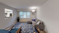 This single-floor residence offers a thoughtfully designed layout that balances comfort and functionality across its key living spaces. The bedroom is a serene retreat, finished with soft carpeting, neutral gray walls, and a window with blinds that allows natural light to filter in while maintaining privacy. Colorful abstract artwork adorns the walls, adding a creative touch to the calm atmosphere.

The living area is open and welcoming, featuring light-toned flooring and a large window that frames views of lush greenery outside, filling the room with natural light. The space comfortably accommodates a sectional sofa and features clean, simple lines throughout.

The kitchen is well-equipped with stainless steel appliances, including a gas range, microwave, and refrigerator. White shaker-style cabinetry pairs with light granite-look countertops and a classic subway tile backsplash, all set over warm wood-tone flooring. A window above the countertop keeps the space bright and airy.

The bathroom is clean and functional, featuring a full-size soaking tub with a tiled shower surround, brushed nickel fixtures, a white vanity, and wood-tone flooring that ties the space together cohesively. Overall, the residence presents a modern, neutral aesthetic that is both practical and inviting.