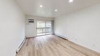 Located at 840 Cherry Valley Road in Vernon Hills, Illinois, this 2-bedroom, 1-bathroom unit offers a well-organized, single-floor layout with a clean, modern aesthetic throughout. The combined living and dining area is bright and open, featuring light wood-look plank flooring, crisp white walls, recessed lighting, and a ceiling fan. A pass-through counter connects the living space to the kitchen and adds a sense of openness. Sliding glass doors lead to a private balcony, bringing in natural light and outdoor views of the surrounding greenery. The kitchen is equipped with rich dark-espresso cabinetry, granite-style countertops, tile flooring, a dishwasher, and a full-size refrigerator. The primary bedroom is a comfortable, well-proportioned room with plush carpeting, a ceiling fan, a natural light window, and baseboard heating. The second bedroom is equally well-appointed with soft carpeting and white walls. The full bathroom features tile flooring, a granite-top vanity with dark cabinetry, and a tiled tub-shower surround. The unit also includes five closets distributed throughout, providing generous storage. A hallway connects the key spaces efficiently, completing this functional and tidy floor plan.
