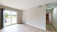 This single-floor space offers a clean, contemporary design with a neutral color palette of soft beige and white tones throughout. The open living areas feature light hardwood-style flooring that flows seamlessly from room to room, while large sliding glass doors allow abundant natural light and provide views of the surrounding greenery outdoors. A stylish globe pendant light fixture adds a decorative touch to the dining or entryway area.

The galley-style kitchen is well-equipped with white shaker cabinetry, marble-look countertops, stainless steel appliances including a refrigerator, electric range, microwave, and dishwasher, all accented by matte black hardware and a black-finish faucet over a stainless steel sink.

The bedrooms are finished with plush wall-to-wall carpeting and ceiling fans for year-round comfort. One bedroom features a closet with direct access to a full bathroom, adding a practical en-suite quality to the layout. The bathrooms are outfitted with clean white vanities, matte black fixtures, mirrored medicine cabinets, and a full soaking tub with shower. Throughout the space, white baseboards, neutral walls, and consistent modern hardware create a cohesive and move-in-ready aesthetic.