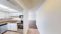 The Summit West Two Bedroom B1 floor plan is a thoughtfully designed single-story residence featuring two bedrooms, one bathroom, and two closets. The kitchen is equipped with stainless steel appliances including a refrigerator, electric range, microwave, and dishwasher, complemented by granite countertops, white shaker cabinetry, a subway tile backsplash, and tile flooring beneath a panel ceiling light fixture. The kitchen flows conveniently toward the combined living area. The living room is spacious and bright, featuring wood-style plank flooring, a textured ceiling, a ceiling fan with light, and a sliding glass door that opens to an outdoor patio, allowing generous natural light to fill the space. Both bedrooms continue the wood-style flooring and are fitted with ceiling fans and windows that bring in natural light. Each bedroom benefits from dedicated closet space, including a walk-in style closet with built-in shelving and hanging rods. The bathroom features a tub/shower combination with full stone-look tile surround. Neutral wall tones and consistent flooring throughout the unit create a cohesive and clean aesthetic well-suited for comfortable everyday living.