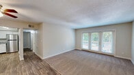 Located at 2041 Shady Grove Way in Louisville, KY, this single-floor, 2-bedroom, 1-bathroom home offers a practical and well-appointed layout. The living room is a welcoming, open space featuring a combination of wood-style hard flooring and plush carpeting, with large double doors that invite natural light and provide access to an outdoor area with lush greenery views. A ceiling fan enhances comfort in the adjacent dining area, which flows seamlessly into the kitchen. The kitchen is well-equipped with white shaker-style cabinetry, granite-look countertops, a double stainless steel sink, and stainless steel appliances, including a dishwasher and range. The two bedrooms are carpeted and feature neutral tones, textured ceilings, and dedicated closet space — four closets total throughout the home provide ample storage. Natural light filters into the secondary bedroom through a window with blinds. The full bathroom includes a soaking tub and shower combination with marble-style surround walls and wood-style flooring. A hallway connects the main living areas to the private spaces, and the entry area features wood-style flooring with access to two doors. The home's neutral color palette and clean finishes create a move-in-ready environment throughout.