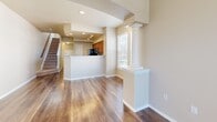 This three-story home in Denver, Colorado offers a well-appointed layout with thoughtful architectural details throughout. The main living area features rich hardwood flooring and is anchored by elegant decorative columns that frame the open-concept space, creating a natural flow between the living and dining areas. A gas fireplace with a granite surround adds warmth and character, complemented by large windows with blinds that fill the room with natural light and offer views of the surrounding greenery.

The kitchen is outfitted with warm-toned cabinetry, granite countertops, a breakfast bar, and stainless steel appliances, including a refrigerator, electric range, and built-in microwave. Recessed lighting and an adjacent window brighten the workspace. A half bath on the main level features a rich wood vanity with granite countertop and pendant lighting.

The upper floors include carpeted bedrooms, each equipped with ceiling fans and generous windows that invite natural light. The bathrooms feature tiled tub-shower combinations, hardwood flooring, and clean, neutral finishes throughout. Stairs connect the three levels seamlessly. The neutral warm palette, consistent use of granite and hardwood, and abundance of natural light create a cohesive and inviting atmosphere throughout the home.