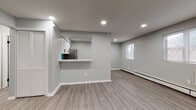 This thoughtfully updated single-floor unit showcases a clean, modern aesthetic throughout, highlighted by a neutral gray palette, white trim, and durable light-toned laminate flooring across the main living areas. The open-concept layout connects a spacious living room to the kitchen via a convenient pass-through breakfast bar, creating an airy and functional flow. The kitchen is well-appointed with crisp white shaker cabinets, light countertops, a teal subway tile backsplash, and a full suite of stainless steel appliances including a refrigerator, range, and over-the-range microwave. Recessed lighting throughout the main living areas adds a polished touch, while baseboard heating and a wall-mounted air conditioning unit ensure year-round comfort. The living space features multiple windows that invite natural light and outdoor views. Bedrooms are finished with plush wall-to-wall carpeting and baseboard heating, offering a warm and comfortable retreat. The bathroom is a standout feature, boasting bold teal glazed subway tile surrounding the tub and shower, paired with matte black fixtures, a white vanity, and large-format gray floor tile — a striking contrast to the otherwise understated design. A dedicated entryway with closet storage completes this well-designed unit.