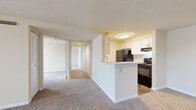 Located at 6945 Regents Ct in Frederick, Maryland, this single-floor residence offers a thoughtfully arranged layout that balances open communal spaces with private living areas. The entry foyer features wood-look plank flooring that transitions into plush wall-to-wall carpeting throughout the main living areas and bedrooms, creating a warm and cohesive feel across the unit.

The open-concept living and dining area is generously proportioned, allowing for flexible furniture arrangements. A pass-through peninsula connects this space to the galley-style kitchen, which is equipped with white cabinetry, light countertops, a stainless steel sink, and black appliances including a refrigerator, electric range, and dishwasher. A louvered pantry door provides convenient storage within the kitchen.

A hallway leads to the bedrooms, each finished with soft carpeting, neutral walls, and windows that admit natural light and views of the surrounding neighborhood. The primary bedroom includes a ceiling fan and direct access to a private bathroom, while an additional bedroom also features a ceiling fan and its own window. The bathroom includes wood-look flooring, a tub-shower combination, and a vanity with ample cabinetry. Textured ceilings are present throughout, contributing to the unit's classic residential character.