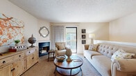 Located at 777 N Silver Springs Blvd in Wichita, Kansas, this two-bedroom, two-bathroom residence offers a well-organized layout across a single level with carpeted stairs visible from images, suggesting a multi-level interior design. The living room serves as the heart of the home, anchored by a classic fireplace and a sliding glass door that opens to a private balcony, allowing natural light to flow in. Soft carpet underfoot and a textured ceiling add warmth and character to the space. Adjacent to the living area is a dedicated dining space, complete with a ceiling fan and room for casual or formal dining. The galley-style kitchen is efficiently designed with abundant wood cabinetry lining both walls, ample counter space, and a full suite of appliances, with a pantry conveniently accessible at the end. Both bedrooms are comfortably proportioned, featuring plush carpet, neutral walls, and closets with built-in shelving for organized storage. The primary bedroom offers a notably generous closet. The bathrooms include a full tub-shower combination with clean white tile surround. Throughout the residence, the overall ambiance is warm and functional, making it a practical and comfortable home in a convenient Wichita location.