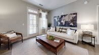 This 2-bedroom, 2-bathroom residence in Augusta, Georgia offers a clean, modern aesthetic with warm neutral tones and wood-look flooring throughout. The open-concept living area is anchored by a bright living room with large windows and a glass-paned door that invites abundant natural light and outdoor views. The kitchen is a standout feature, showcasing light wood cabinetry, granite countertops, stainless steel appliances, pendant lighting, and a spacious island with bar seating — ideal for both cooking and casual dining. A dedicated dining area with a pendant chandelier and an octagonal mirror adds an elegant touch. The primary bedroom is generously sized with plush carpeting, a ceiling fan, and large windows, while the second bedroom offers a similarly comfortable and well-lit retreat. The primary bathroom features a walk-in glass-enclosed shower with tile surround and a modern vanity with ample storage. The second bathroom includes a full soaking tub with tiled surround and a matching vanity. A dedicated laundry room with a full-size washer and dryer provides added convenience. Throughout the residence, soft gray walls, modern fixtures, and consistent finishes create a cohesive and inviting atmosphere.