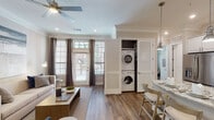 This single-story, one-bedroom, one-bathroom residence in Houston, TX offers a thoughtfully designed open-concept layout finished with warm hardwood-style flooring and crown molding throughout. The living area is bright and welcoming, featuring large windows that invite natural light and a ceiling fan overhead. A dedicated dining nook with a marble-top table sits adjacent to the living space, creating a functional yet refined area for everyday use.

The kitchen is a standout feature, equipped with white shaker cabinetry, a subway tile backsplash, granite countertops, stainless steel appliances, and a center island with seating — all illuminated by pendant lighting. A convenient in-unit stacked washer and dryer is neatly tucked behind louvered doors within the main living area.

The bedroom offers a spacious, serene retreat with a ceiling fan, generous natural light from dual windows, and access to a well-organized walk-in closet with built-in shelving. The bathroom features a full tub and shower combination with marble-style tile surround and marble flooring, complemented by clean, neutral finishes. The overall ambiance is polished and contemporary, with cohesive neutral tones creating a calm, livable environment throughout.