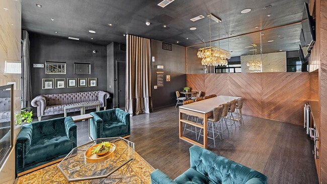 Resident lounge with plush seating, wood style floor, and large TVs. - Griffis Oak Lawn