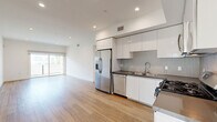 Located in the heart of Los Angeles, this modern 2-bedroom, 1-bathroom residence at 518 N Gramercy Place offers a clean, contemporary design throughout. The open-concept living, dining, and kitchen area serves as the heart of the home, featuring warm wood-tone flooring that extends seamlessly across the entire space. The kitchen is outfitted with sleek white cabinetry, dark countertops, a patterned tile backsplash, and a full suite of stainless steel appliances including a French door refrigerator, gas range, built-in microwave, and dishwasher. The living area is bright and airy, with recessed lighting and a sliding glass door that opens to a private balcony with outdoor views. Both bedrooms are well-proportioned, bathed in natural light, and feature the same consistent wood-tone flooring and crisp white walls. The spacious primary bedroom includes access to a generously sized walk-in closet with built-in shelving, hanging rods, and integrated drawers for ample storage. The full bathroom is finished with large-format tile flooring, a white vanity with dark countertops, dual mirrors, and a tub-shower combination with sliding glass doors. In-unit laundry and additional closet space complete this well-appointed home.