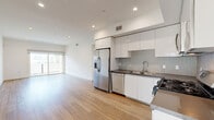 Located in the heart of Los Angeles, this modern 2-bedroom, 1-bathroom residence at 518 N Gramercy Place offers a clean, contemporary design throughout. The open-concept living, dining, and kitchen area serves as the heart of the home, featuring warm wood-tone flooring that extends seamlessly across the entire space. The kitchen is outfitted with sleek white cabinetry, dark countertops, a patterned tile backsplash, and a full suite of stainless steel appliances including a French door refrigerator, gas range, built-in microwave, and dishwasher. The living area is bright and airy, with recessed lighting and a sliding glass door that opens to a private balcony with outdoor views. Both bedrooms are well-proportioned, bathed in natural light, and feature the same consistent wood-tone flooring and crisp white walls. The spacious primary bedroom includes access to a generously sized walk-in closet with built-in shelving, hanging rods, and integrated drawers for ample storage. The full bathroom is finished with large-format tile flooring, a white vanity with dark countertops, dual mirrors, and a tub-shower combination with sliding glass doors. In-unit laundry and additional closet space complete this well-appointed home.