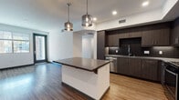 Located at 1333 N Santa Fe Ave in Vista, California, this single-floor residence showcases a clean, modern design with high-quality finishes throughout. The open-concept layout connects the living area and kitchen, creating a seamless flow ideal for everyday living and entertaining.

The kitchen is a standout feature, outfitted with dark espresso cabinetry, a textured dark tile backsplash, and a full suite of stainless steel appliances including a refrigerator, range, microwave, and dishwasher. A central island with a quartz countertop and bar overhang provides additional prep space and seating, illuminated by a pair of stylish glass pendant lights. Warm hardwood-style flooring extends throughout the main living areas, adding brightness and continuity to the space.

The bathroom is well-appointed with dark wood cabinetry, quartz countertops, an undermount sink, a large wall mirror, and a full soaking tub with a sliding glass enclosure and white tile surround. Wood-look flooring continues into this space for a cohesive aesthetic.

A spacious walk-in closet with built-in shelving and hanging rods offers generous storage. Recessed lighting throughout ensures the space is well-lit, and the clean white walls create a bright, airy ambiance across every room.