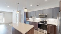 Located at 2622 Fairview Dr in Alexandria, VA, this single-floor residence showcases a thoughtfully designed, modern interior with high-quality finishes throughout. The open-concept kitchen serves as a central highlight, featuring a two-tone cabinet design that pairs gray shaker-style upper cabinets with warm wood-toned lower cabinets. A marble-inspired tile backsplash complements the light quartz countertops, while a generously sized center island provides additional workspace and casual seating. Pendant globe lighting adds a contemporary touch overhead, and a full suite of stainless steel appliances—including a refrigerator, electric range, microwave, and dishwasher—completes the space. Light wood-look flooring flows seamlessly through the kitchen and living areas.

The living room is bright and airy, benefiting from natural light streaming through glass doors that open to an outdoor view, accented by a ceiling fan. The bedroom features plush carpeting, a ceiling fan, and a wide window offering natural light. A walk-in closet with wire shelving provides organized storage. The primary bathroom includes a dual-sink vanity with gray cabinetry, a large mirror, and a tub-shower combination with marble-style tile. A secondary bathroom offers a single-sink vanity with dark wood cabinetry and a glass-enclosed shower, finished with elegant tile flooring.