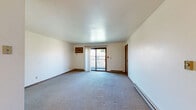 Located at 2209 Michelle Ct in Appleton, Wisconsin, this single-floor, 2-bedroom, 1-bathroom residence offers a practical and well-organized layout. The living area is carpeted and bright, featuring a sliding glass door that opens to a private balcony overlooking outdoor greenery, allowing natural light to fill the space. Baseboard heating is present throughout, providing efficient warmth suited to Wisconsin's climate. The kitchen is equipped with warm-toned wood cabinetry, light countertops, and a stainless electric range, all complemented by durable hardwood-style flooring that adds a clean, functional aesthetic. The primary bedroom offers a comfortable footprint with a double sliding-door closet, a window with blinds, and carpeted flooring. The second bedroom is similarly carpeted and well-lit, featuring a ceiling fan with light fixture, a window, and a baseboard heater. Both bedrooms include wood-toned closet doors consistent with the home's interior design language. The full bathroom features a single-sink vanity with wood cabinetry, a tub-shower combination, and hardwood-style flooring. Throughout the home, warm wood accents on doors and trim provide a cohesive and inviting atmosphere.