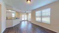 Located at 21739 Hardy Oak Blvd in San Antonio, Texas, this single-floor unit offers a thoughtfully designed layout that balances comfort and functionality. The open-concept living and dining area is a standout feature, showcasing rich, dark hardwood-style flooring, crown molding, and warm neutral-toned walls that create a bright and welcoming atmosphere. Large windows fitted with blinds allow generous natural light to fill the space, while a set of glass-panel doors leads to the exterior, further enhancing the sense of openness. A pendant light fixture adds a decorative touch to the dining area.

The kitchen is positioned adjacent to the living area and features an efficient layout with warm wood cabinetry, tile backsplash, and a full suite of black appliances including a gas range, microwave, dishwasher, and refrigerator. A raised breakfast bar provides a convenient pass-through to the main living space.

The bedroom is generously sized, finished with plush carpeting and a ceiling fan, and includes access to a closet and a well-appointed full bathroom. The bathroom is equipped with a combined tub and shower, a wood-toned vanity, and durable hardwood-style flooring, completing this functional and comfortable residence.