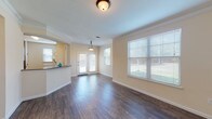 Located at 21739 Hardy Oak Blvd in San Antonio, Texas, this single-floor unit offers a thoughtfully designed layout that balances comfort and functionality. The open-concept living and dining area is a standout feature, showcasing rich, dark hardwood-style flooring, crown molding, and warm neutral-toned walls that create a bright and welcoming atmosphere. Large windows fitted with blinds allow generous natural light to fill the space, while a set of glass-panel doors leads to the exterior, further enhancing the sense of openness. A pendant light fixture adds a decorative touch to the dining area.

The kitchen is positioned adjacent to the living area and features an efficient layout with warm wood cabinetry, tile backsplash, and a full suite of black appliances including a gas range, microwave, dishwasher, and refrigerator. A raised breakfast bar provides a convenient pass-through to the main living space.

The bedroom is generously sized, finished with plush carpeting and a ceiling fan, and includes access to a closet and a well-appointed full bathroom. The bathroom is equipped with a combined tub and shower, a wood-toned vanity, and durable hardwood-style flooring, completing this functional and comfortable residence.