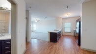This single-story residence offers a well-organized layout that seamlessly connects its main living areas. The open-concept kitchen and living space serves as the heart of the home, where warm wood-look flooring extends throughout the common areas. The kitchen is equipped with dark espresso cabinetry, light countertops, a subway tile backsplash, and black stainless appliances, including a refrigerator and electric range. A peninsula with a built-in sink provides additional workspace and casual dining potential, while a dedicated window allows natural light to brighten the cooking area.

The adjacent living space is carpeted and generously proportioned, featuring a ceiling fan and natural light from multiple windows. The open sightlines between the kitchen and living room enhance the sense of connectivity and spaciousness throughout.

The bedrooms are carpeted for comfort, each equipped with a ceiling fan. One bedroom features dual windows that bring in ample natural light and includes access to a walk-in closet. The bathroom is finished with dark wood vanity cabinetry, a light stone-look countertop, wood-look flooring, and a full tub-shower combination with built-in shelving. The overall palette of neutral tones and consistent finishes creates a clean, cohesive ambiance throughout the space.