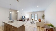Located at 267 Seminole Rd in Norton Shores, Michigan, this well-appointed 2-bedroom, 2-bathroom single-floor residence offers a thoughtfully designed layout with modern finishes throughout. The open-concept kitchen and living area serves as the heart of the home, where light wood-tone cabinetry, granite countertops, and a large center island with bar seating create a functional and stylish space. Pendant lighting accents the island, while stainless steel appliances—including a range, microwave, and refrigerator—complete the kitchen. The living area extends naturally from the kitchen, featuring light hardwood-style flooring, recessed lighting, and French doors that invite natural light and provide outdoor access. The two bedrooms are carpeted and comfortably sized, with the primary bedroom offering a generous footprint, a large window with natural light, and ample closet space. The second bedroom also includes its own closet. Two bathrooms serve the home; one features a granite-topped vanity with stylish cabinetry and a shower, while the other is conveniently combined with the laundry area. Four closets throughout the unit provide excellent storage. The neutral color palette and clean architectural lines give the space a bright, contemporary ambiance.