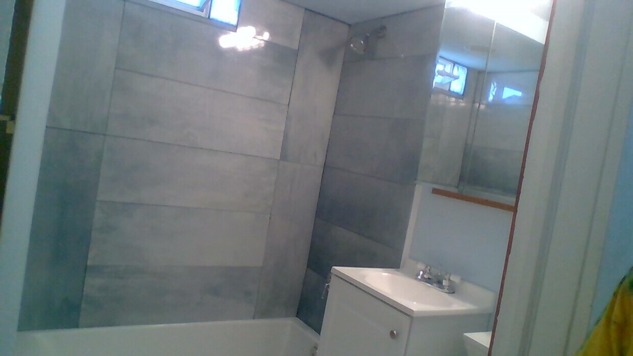 Bath with new tub, tile, shower, sink, toilet, and window. - 942 Troost Ave