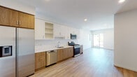 Located at 505 Silver Lake Blvd in the sought-after Silver Lake neighborhood of Los Angeles, this contemporary single-floor residence showcases a clean, modern design with light wood-tone flooring running throughout and a bright, neutral color palette that creates a cohesive and inviting atmosphere.

The kitchen is a standout feature, thoughtfully designed with a two-tone cabinetry scheme combining white upper cabinets and warm wood-grain lower cabinets. A white subway tile backsplash, quartz countertops, and a central island with matching wood paneling add both style and functionality. Stainless steel appliances — including a gas range, over-the-range microwave, refrigerator, and dishwasher — complete this well-appointed space.

The open-concept layout connects the kitchen seamlessly to the living area, which is bathed in natural light from a sliding glass door that leads to a private balcony framed by a decorative lattice screen. The balcony offers pleasant views of the surrounding Silver Lake neighborhood and tree-lined surroundings.

The bedroom is generously proportioned with recessed lighting and a sliding frosted-glass closet, providing ample storage. The bathroom features large-format tile flooring, a combined soaking tub and shower enclosed by sliding glass doors, and clean white fixtures throughout. The overall ambiance of this residence is modern, bright, and move-in ready.