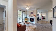 This single-floor residence offers a thoughtfully designed layout that balances comfort and functionality throughout. The living room serves as the heart of the home, featuring a white-mantled fireplace as a focal point, plush carpeting, crown molding, and a ceiling fan overhead. Large sliding glass doors flood the space with natural light and open onto a private balcony with outdoor seating, offering pleasant views of surrounding greenery. The living area flows seamlessly into a dining space and an open-concept kitchen, which is equipped with white cabinetry, track lighting, a double sink, and a peninsula island with bar seating — ideal for casual dining or entertaining. The kitchen connects directly to the dining area and provides easy access to the bedrooms beyond. The bedrooms are carpeted and well-sized, each featuring ceiling fans or ample natural light from large windows with views of the outdoors, and access to walk-in closets. The bathroom is clean and bright, finished with wood-look flooring, white cabinetry, a soaking tub, and a separate glass-enclosed shower. Crown molding and consistent neutral tones throughout the space lend a cohesive, polished aesthetic to this inviting residence.