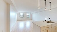 Located at 758 N Broadway in Milwaukee's vibrant lower east side, this well-designed one-bedroom, one-bathroom unit offers a clean, modern aesthetic across a thoughtfully laid-out single floor. Light bamboo hardwood flooring runs throughout the main living areas, lending warmth to the bright, white-walled interior.

The open-concept kitchen and living room form the heart of the unit. The kitchen is outfitted with white flat-panel cabinetry, stainless steel appliances including a full-size refrigerator, microwave, and electric range, and a large center island with a quartz countertop, double basin sink with a matte black faucet, and pendant lighting overhead — ideal for both cooking and casual dining.

The spacious living area benefits from dual windows that bring in natural light and offer urban views of the surrounding neighborhood. A hallway leads to the private bedroom, which features its own window with city views and direct access to a well-organized walk-in closet with wire shelving systems. A second closet provides additional storage.

The bathroom is finished with classic black-and-white hexagonal tile flooring, a glass-enclosed walk-in shower with subway tile surround, and a vanity with ample counter space. Recessed lighting completes the clean, polished look of this contemporary Milwaukee residence.