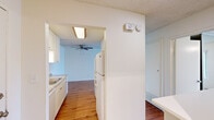 Located at 5757 Lake Murray Blvd in La Mesa, California, this one-bedroom, one-bathroom residence offers a well-organized single-floor layout designed for comfortable everyday living. The kitchen is thoughtfully equipped with white shaker-style cabinetry, granite-patterned countertops, a double stainless steel sink, and white appliances, all set atop warm wood-look flooring that carries throughout the main living areas. Recessed and flush-mount lighting illuminates the space efficiently, while a ceiling fan in the adjacent living area promotes year-round comfort. The bedroom is carpeted for warmth and features full-panel mirrored sliding closet doors that enhance the sense of space, along with a ceiling fan and windows with vertical blinds that frame pleasant outdoor views of the surrounding La Mesa neighborhood. The bathroom is finished with a large vanity topped with a striking marble-patterned countertop, a wide mirror, and bright overhead lighting. A textured ceiling is present throughout the unit, lending a classic residential character. The layout flows naturally from the kitchen through to the living and sleeping areas, making efficient use of the available footprint while maintaining a clean, cohesive aesthetic throughout.