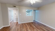This single-story, 3-bedroom, 2-bathroom home offers a practical and comfortable layout designed to maximize everyday living. Warm hardwood-style flooring flows consistently throughout the home, complemented by neutral beige walls and clean white trim that create a bright, cohesive aesthetic.

The living room is a welcoming space featuring a ceiling fan with light fixture, a pass-through window connecting to the kitchen, and direct access to additional rooms via a central hallway. The kitchen is well-equipped with white cabinetry, granite-style countertops, a tile backsplash, and white appliances including a range, dishwasher, and microwave. A door from the kitchen provides convenient exterior access.

Each of the three bedrooms features hardwood-style flooring, ceiling fans, and windows fitted with white horizontal blinds that allow for natural light control. The primary bedroom is generously proportioned and includes a sliding closet. Additional bedrooms offer closeted storage, including a bi-fold door closet in one room. The home also includes four closets total, a utility room, and a dedicated laundry area.

Both bathrooms feature white subway tile surrounds in the tub-shower combinations, with one bathroom offering a window for natural light and granite-style countertops. The home's efficient, single-level design and ample storage make it a functional and comfortable living space.