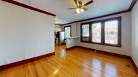 Located at 622 Harrison St in the historic village of Oak Park, IL, this single-floor residence showcases classic craftsman character throughout. Rich dark wood trim, crown molding, and warm hardwood floors run continuously through the living spaces, lending a cohesive and timeless aesthetic.

The open living area greets you with natural light streaming through large, dark-framed windows and is finished with a ceiling fan overhead. It flows seamlessly into the kitchen, which is separated by a convenient breakfast bar. The kitchen is well-appointed with light maple cabinetry, a mosaic tile backsplash, stainless steel appliances including a gas range, microwave, refrigerator, and dishwasher, plus ample counter space.

Multiple bedrooms carry the same hardwood flooring and bold wood trim, each equipped with ceiling fans and cast-iron radiators that speak to the home's vintage character. One bedroom features a built-out closet with organizational shelving, while others offer generous natural light through framed windows. The bathroom is cleanly updated with large-format neutral tile, a soaking tub with a glass shower surround, a white vanity, and a classic cast-iron radiator. The overall ambiance is warm, inviting, and rooted in the architectural heritage of Oak Park.