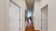 This thoughtfully designed single-floor residence offers 1 bedroom, 2 full bathrooms, a dedicated office, and a closet, all connected by a welcoming hallway finished with rich hardwood flooring. The entry hallway sets an elegant tone, lined with crisp white walls, panel doors with brushed hardware, and framed artwork that guides you toward the main living area. The living room is a bright, airy retreat featuring elevated ceilings, a ceiling fan, and a glazed door with transom window that fills the space with natural light and provides outdoor access. Warm hardwood floors and a curated gallery wall of abstract artwork complete the inviting atmosphere. The bedroom offers a comfortable, light-filled sanctuary with large windows fitted with roller shades, neutral carpeting, and ample space for restful living. Both bathrooms are finished to a high standard, showcasing marble-style tile flooring, granite countertop vanities with undermount sinks and chrome fixtures, and marble-accented walk-in showers. The primary bathroom includes access to a dedicated walk-in closet. The office provides a quiet, functional space ideal for working from home. Throughout the residence, a consistent palette of soft whites and warm neutrals creates a cohesive and refined ambiance.