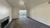 This 590-square-foot, one-bedroom, one-bathroom apartment is located at 900 N Switzer Canyon Dr in Flagstaff, Arizona. The single-floor unit is efficiently laid out, encompassing a combined kitchen and living room, a 160-square-foot bedroom, a full bathroom, and a hallway. The galley-style kitchen is well-appointed with light wood cabinetry lining both walls, white appliances including an electric range and refrigerator, a double-basin sink, and tile flooring with overhead lighting — providing ample storage and counter space for everyday cooking. The living room features plush dark carpeting, a ceiling fan, and a sliding glass door that opens to a private outdoor balcony, allowing natural light and exterior views to fill the space. The bedroom also includes dark carpet flooring, neutral white walls, and a ceiling fan, with a second sliding glass door providing additional outdoor access and natural light. The bathroom features tile flooring, textured walls, recessed lighting, and a functional layout with open hallway space leading to the fixtures. Throughout the unit, clean white walls and neutral finishes create a simple, move-in-ready aesthetic suited for comfortable everyday living in the Flagstaff area.