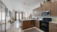Located in Corinth, TX, this thoughtfully designed one-bedroom, one-bathroom residence offers a contemporary living experience across a single, well-appointed floor. The open-concept layout seamlessly connects the kitchen and living room, creating a bright and functional shared space. The kitchen is equipped with stainless steel appliances — including a refrigerator, microwave, and dishwasher — complemented by warm wood-toned cabinetry, granite countertops, a tile backsplash, and a peninsula with bar seating ideal for casual dining. Polished concrete floors extend throughout, lending an industrial-modern aesthetic. The living room is bathed in natural light from floor-to-ceiling glass doors that open to a private balcony, offering outdoor views. The bedroom is a comfortable retreat featuring a large window, ample natural light, and a dedicated closet. The full bathroom includes a tub-shower combination with tile surround and a wood-toned vanity that echoes the kitchen's design language. Clean white walls, recessed and pendant lighting, and a consistent modern finish palette tie the entire space together, resulting in a cohesive and stylish urban residence.