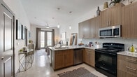 Located in Corinth, TX, this thoughtfully designed one-bedroom, one-bathroom residence offers a contemporary living experience across a single, well-appointed floor. The open-concept layout seamlessly connects the kitchen and living room, creating a bright and functional shared space. The kitchen is equipped with stainless steel appliances — including a refrigerator, microwave, and dishwasher — complemented by warm wood-toned cabinetry, granite countertops, a tile backsplash, and a peninsula with bar seating ideal for casual dining. Polished concrete floors extend throughout, lending an industrial-modern aesthetic. The living room is bathed in natural light from floor-to-ceiling glass doors that open to a private balcony, offering outdoor views. The bedroom is a comfortable retreat featuring a large window, ample natural light, and a dedicated closet. The full bathroom includes a tub-shower combination with tile surround and a wood-toned vanity that echoes the kitchen's design language. Clean white walls, recessed and pendant lighting, and a consistent modern finish palette tie the entire space together, resulting in a cohesive and stylish urban residence.
